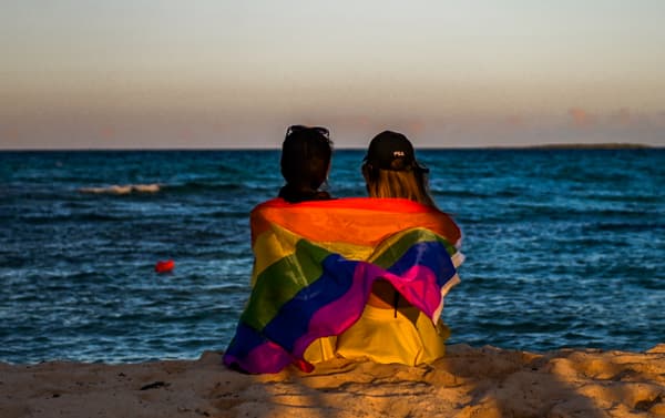Deux femmes assises le long de la plage avec un drapeau LGBT sur les épaules, dans un hôtel de Guillermo Key (Cuba), le 27 novembre 2021. Deux femmes assises le long de la plage avec un drapeau LGBT sur les épaules, dans un hôtel de Guillermo Key (Cuba), le 27 novembre 2021.